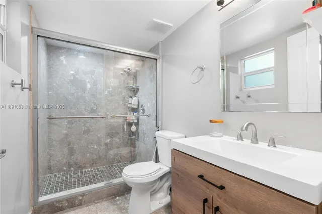 a bathroom with a shower sink vanity mirror and toilet