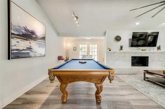 a room with wooden floor pool table and furniture