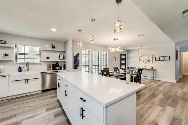 a large white kitchen with lots of counter space a sink appliances and cabinets