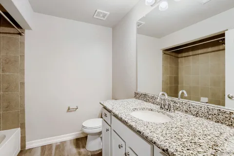 a bathroom with a granite countertop sink toilet and shower