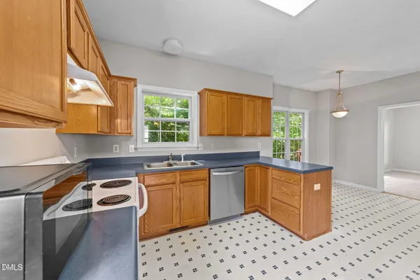 a kitchen with stainless steel appliances a sink a stove a refrigerator cabinets and a window