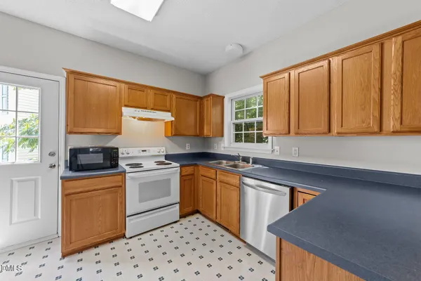 a kitchen with stainless steel appliances a sink a stove a refrigerator cabinets and a window