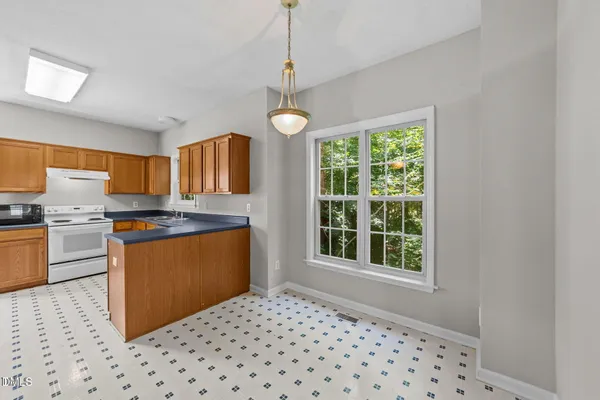 a kitchen with stainless steel appliances granite countertop a refrigerator a sink dishwasher a stove and white countertops with wooden floor