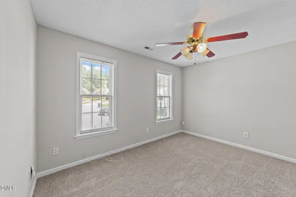 an empty room with windows and chandelier fan