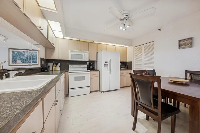 a kitchen with stainless steel appliances granite countertop a sink a stove a refrigerator with a dining table and chairs