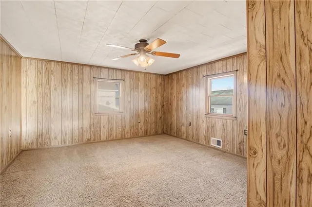 an empty room with chandelier fan and windows