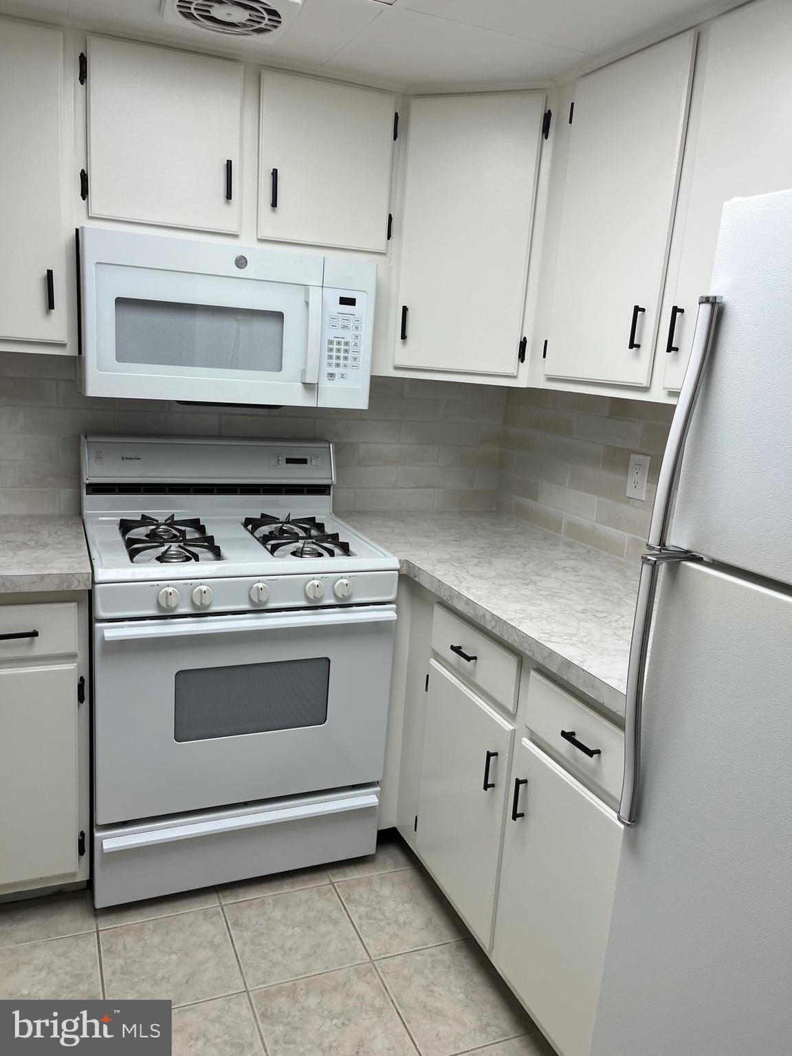 18204-00 Delaire Landing Road, Unit 204 Philadelphia, PA 19114 - Photo 14 of 14 a kitchen with granite countertop white cabinets and white appliances