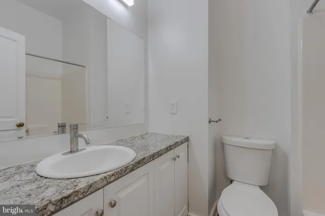 a bathroom with a granite countertop toilet sink and mirror
