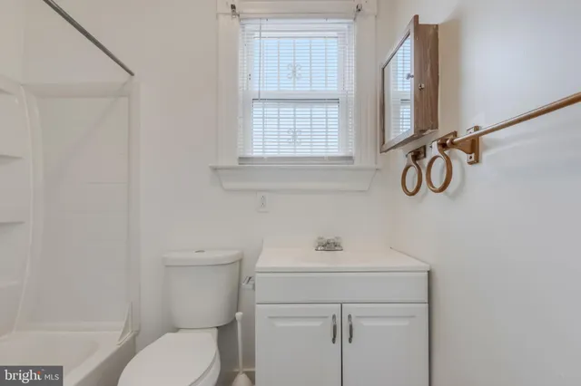 a bathroom with a toilet sink vanity and mirror