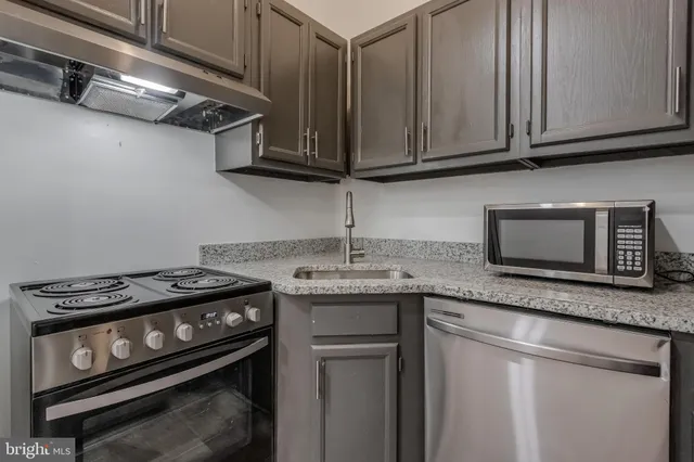 a kitchen with granite countertop a stove sink and cabinets