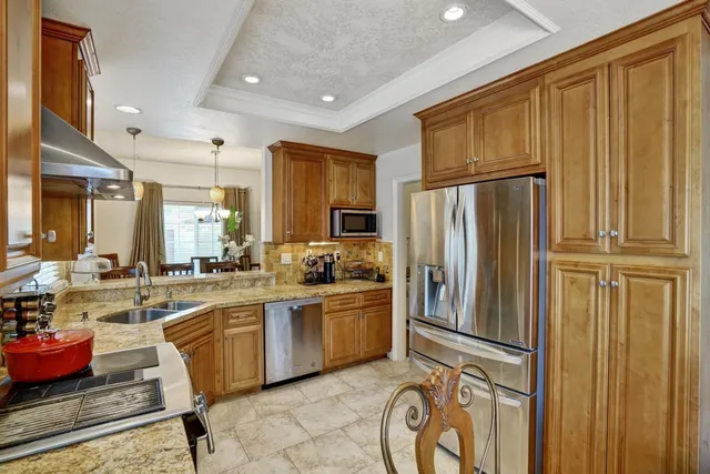 a kitchen with stainless steel appliances granite countertop a refrigerator and a stove top oven