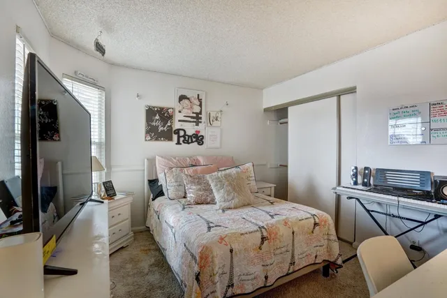 a bedroom with a bed a couch and a flat tv screen on the dresser