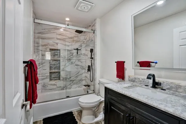 a bathroom with a granite countertop bathtub sink vanity mirror and toilet