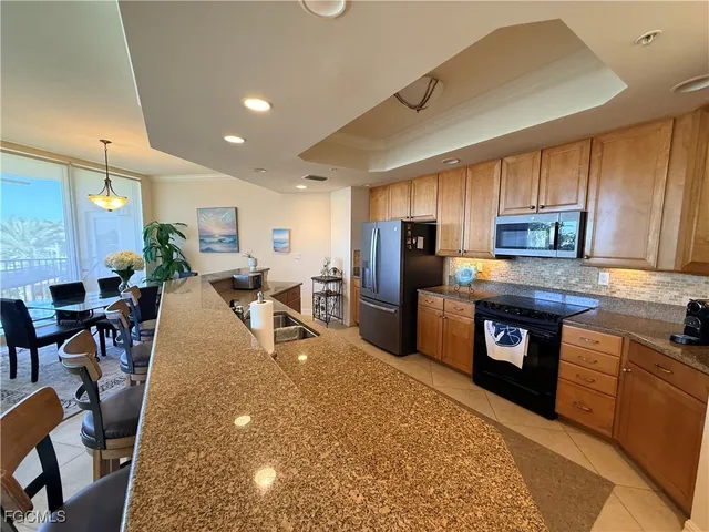 a kitchen with stainless steel appliances granite countertop a refrigerator a stove a sink a dining table and chairs