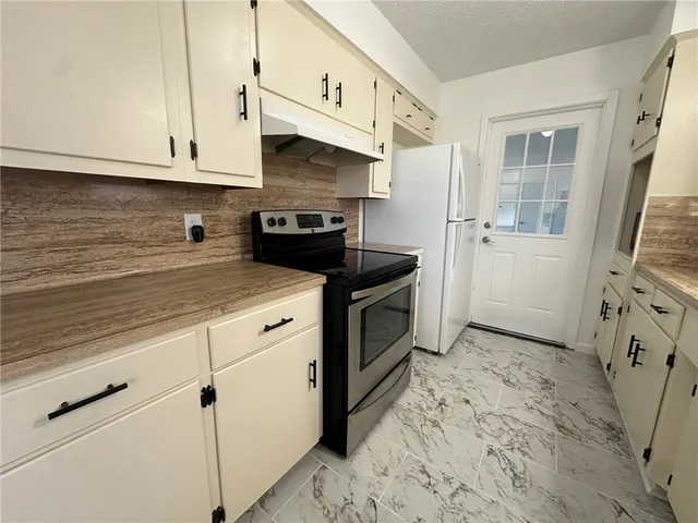 a kitchen with granite countertop a sink stove and cabinets