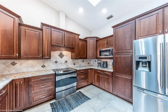 a kitchen with stainless steel appliances granite countertop a sink a stove and a refrigerator