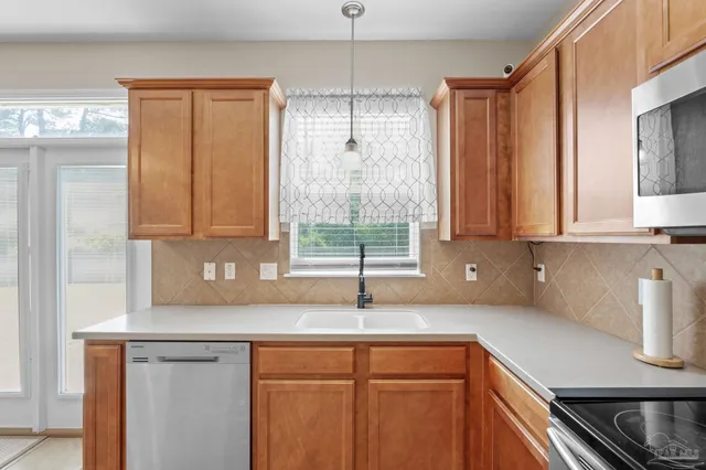 a kitchen with stainless steel appliances granite countertop a sink a window and cabinets