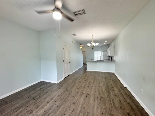 wooden floor in an empty room with a kitchen