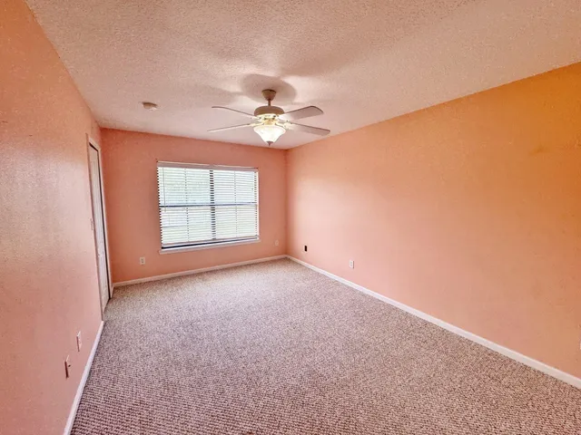 an empty room with windows and ceiling fan