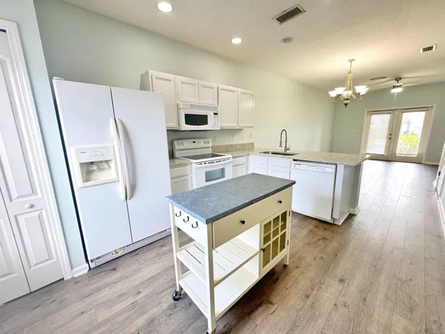 a kitchen with stainless steel appliances a stove a refrigerator a sink a oven with wooden floor and cabinets