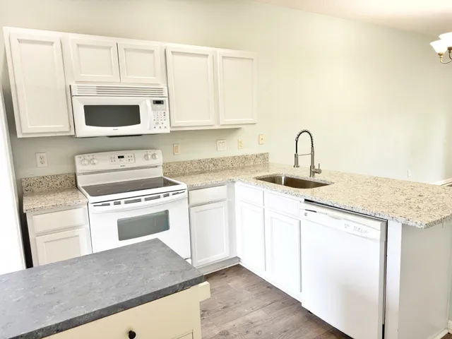 a kitchen with granite countertop a sink cabinets and stainless steel appliances