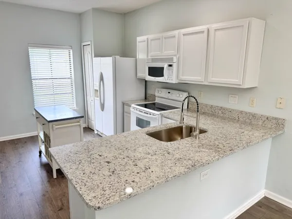 a kitchen with stainless steel appliances granite countertop a sink a microwave a refrigerator and white cabinets