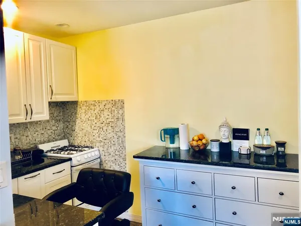a kitchen with stainless steel appliances a sink a stove and white cabinets