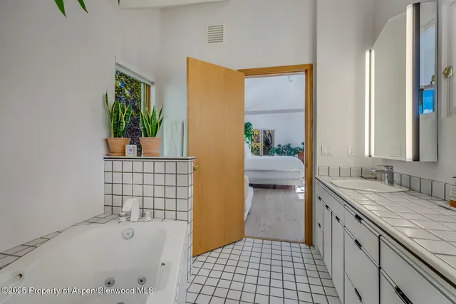 a bathroom with a sink a granite countertop tub and a sink