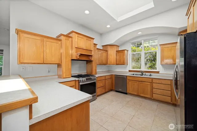 a kitchen with stainless steel appliances granite countertop a stove a sink and a refrigerator