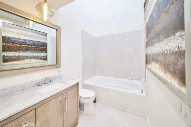 a bathroom with a bathtub shower sink vanity mirror and toilet