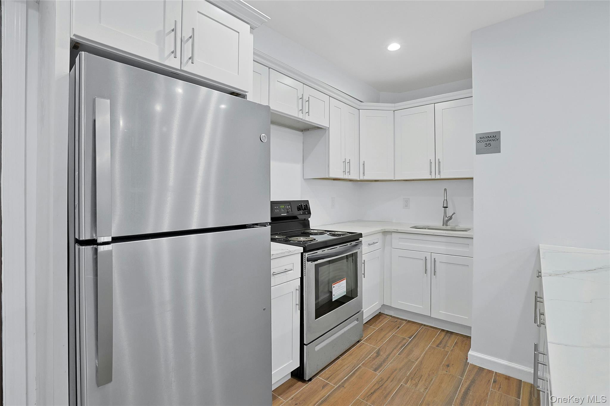 2545 Sedgwick Avenue, Unit 3 Bronx, NY 10468 - Photo 8 of 15 Community view 2 Renovated Kitchen with appliances with stainless steel finishes, white cabinets, wood finish floors, light stone counters, and recessed lighting