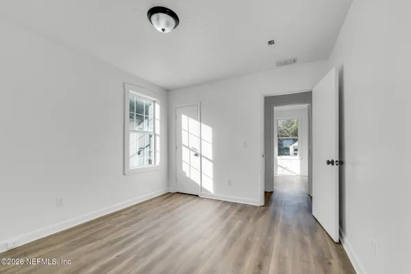 an empty room with wooden floor and windows