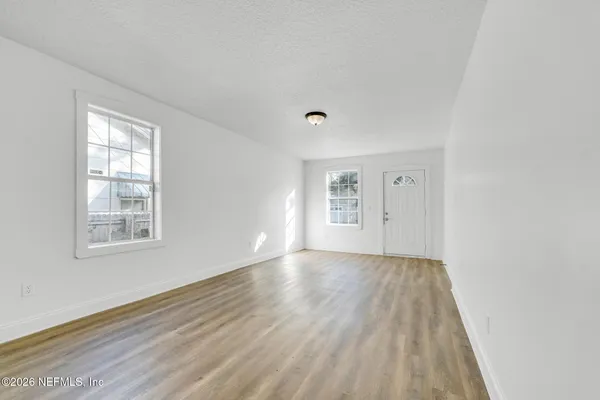 an empty room with wooden floor and windows