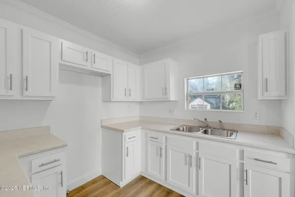 a kitchen with white cabinets and sink