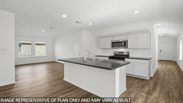 a kitchen with granite countertop a sink and a stove top oven with wooden floor