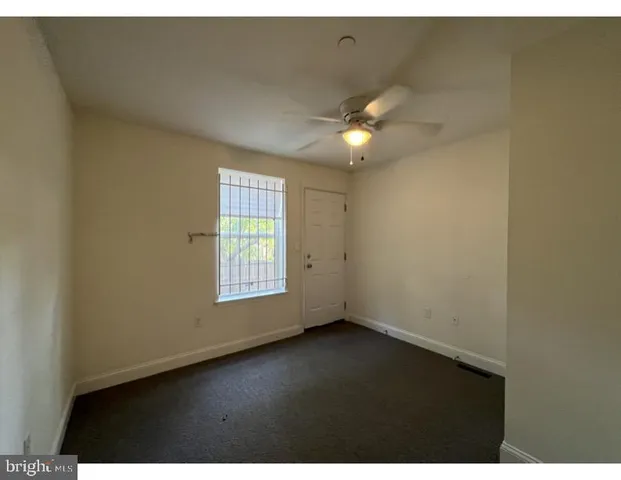 an empty room with a window and a ceiling fan
