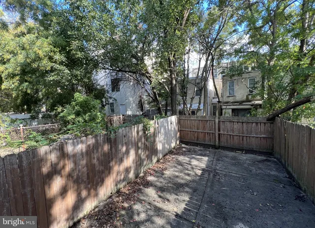 a view of backyard with wooden fence and trees