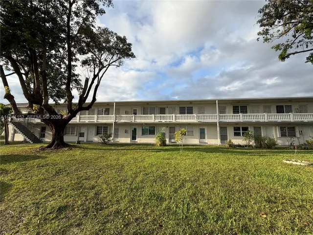 a view of a large building next to a big yard and large trees