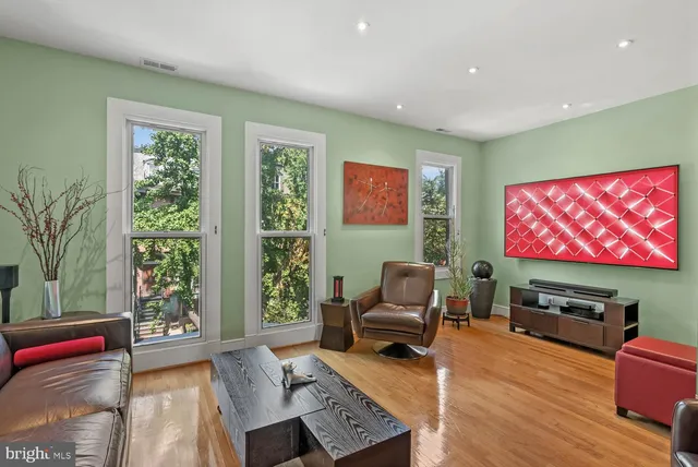 a living room with furniture a flat screen tv and wooden floor