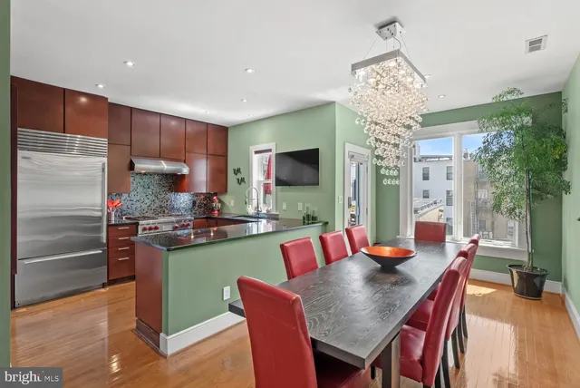 a kitchen with stainless steel appliances granite countertop a table chairs and a chandelier