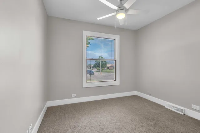 an empty room with a window and a fan