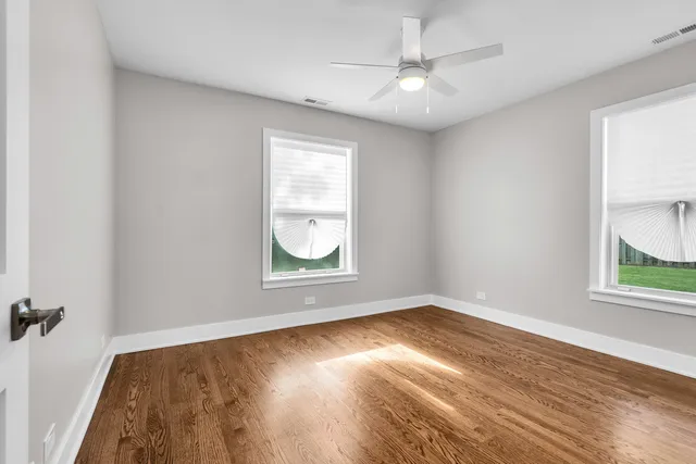 an empty room with windows and fan