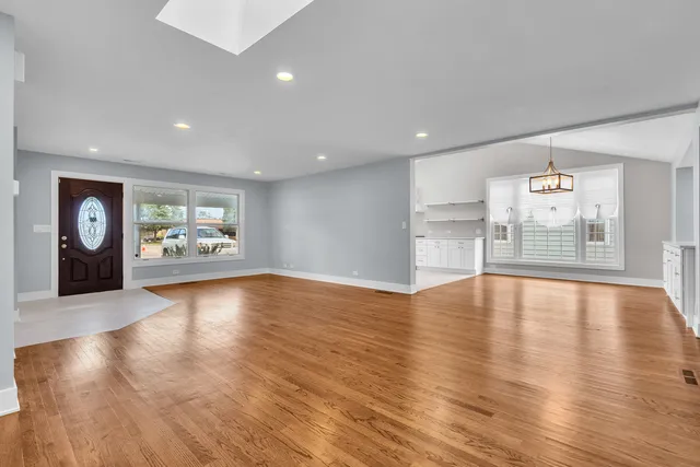 a view of an empty room with window and wooden floor