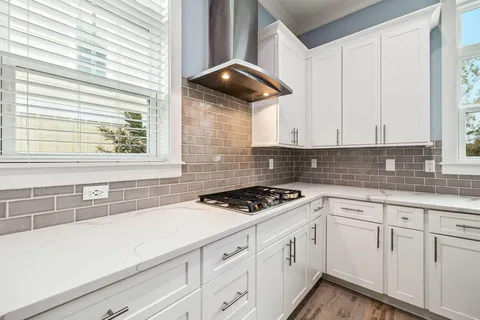 a open kitchen with stainless steel appliances granite countertop a barbecue grill and couches chair with a garden view