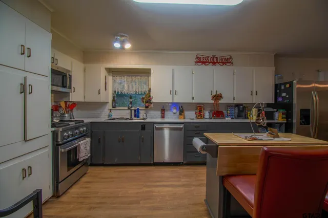 a kitchen with kitchen island granite countertop a sink cabinets and wooden floor