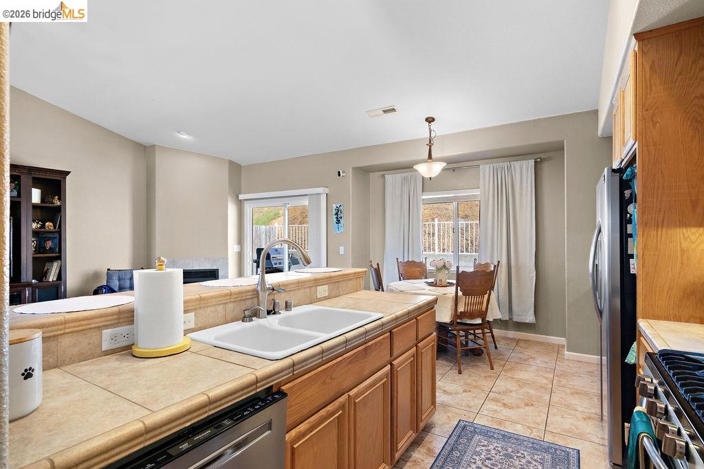 4955 Little John Road Copperopolis, CA 95228 - Photo 26 of 60 Kitchen featuring tile counters, stainless steel appliances, pendant lighting, light tile patterned flooring, and wood finish cabinetry