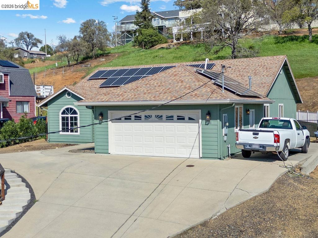 4955 Little John Road Copperopolis, CA 95228 - Photo 38 of 60 View of front of house with roof mounted solar panels, concrete driveway, an attached garage, and a shingled roof
