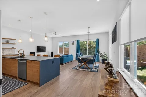 a view of a kitchen with kitchen island granite countertop a large window cabinets a sink and stainless steel appliances