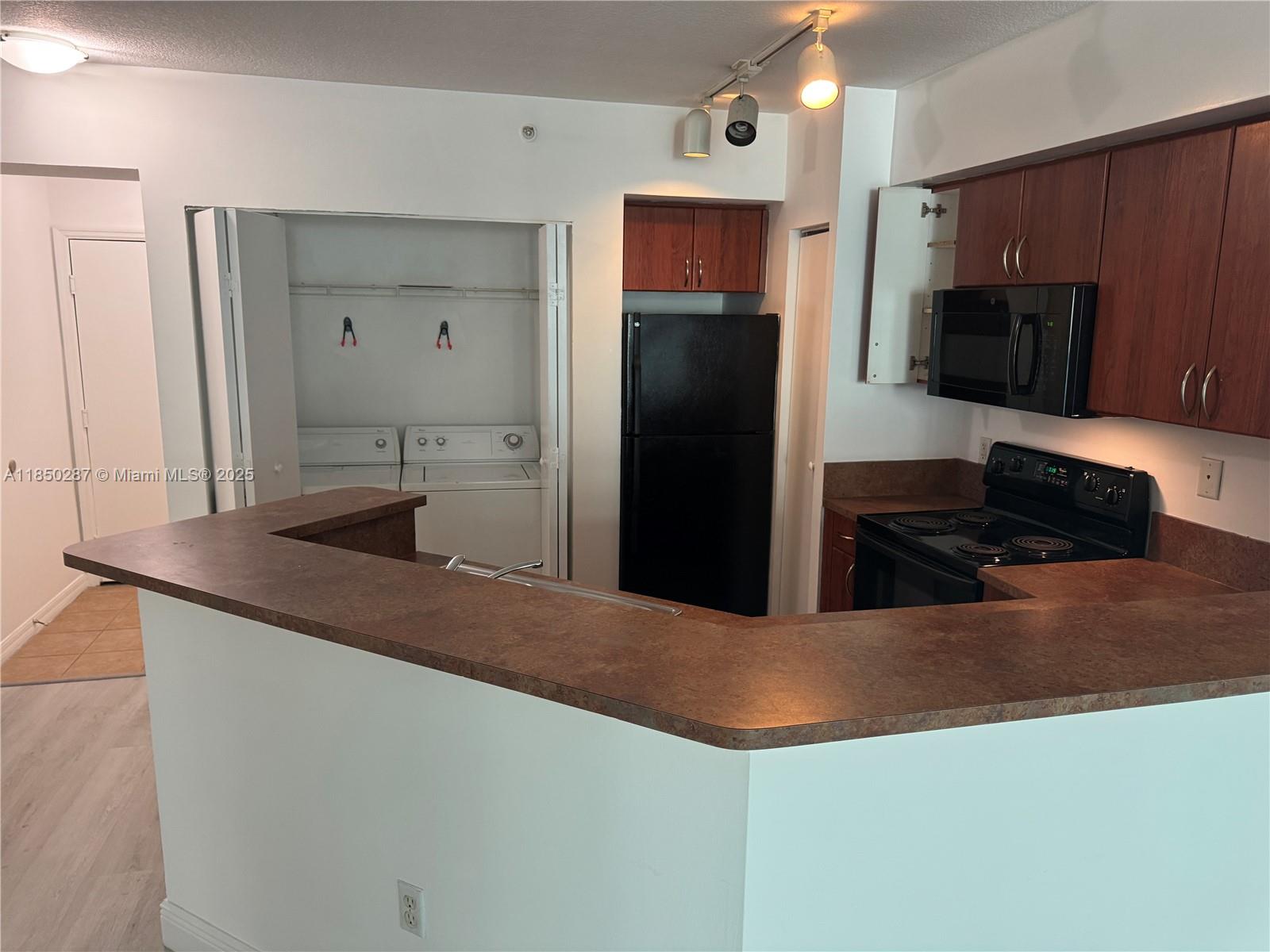 9201 Collins Avenue, Unit 323 Surfside, FL 33154 - Photo 14 of 46 a kitchen with stainless steel appliances kitchen island a sink stove and refrigerator