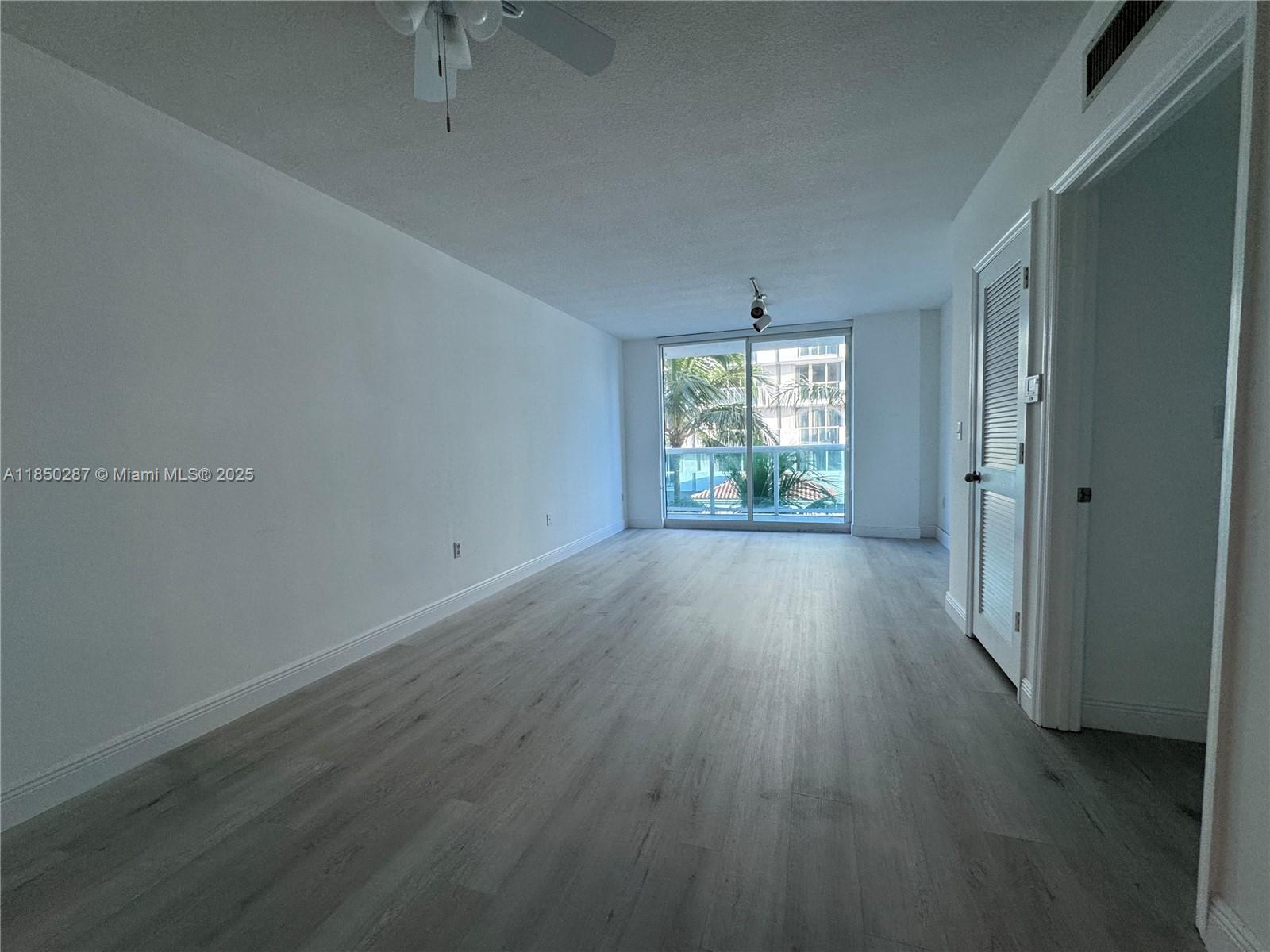 9201 Collins Avenue, Unit 323 Surfside, FL 33154 - Photo 17 of 46 an empty room with wooden floor and windows